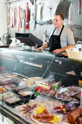 Male seller posing with wursts in butchery