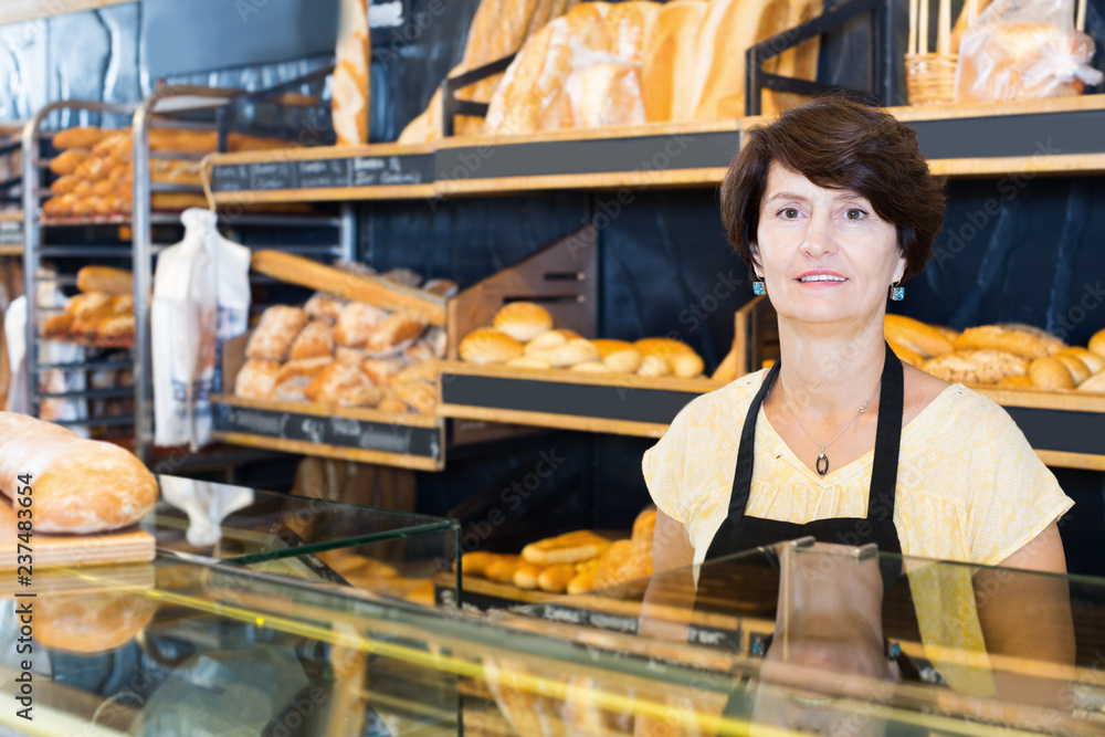 Woman baker with tasty baguettes and other bread products