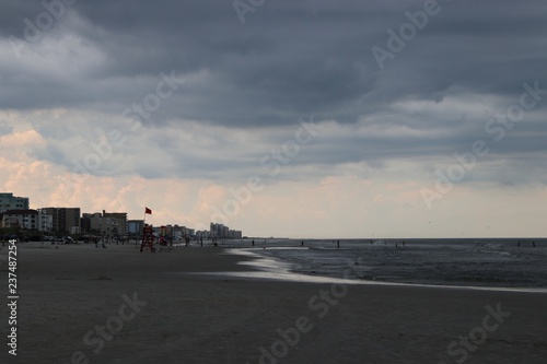 Beautiful beach waves surf horizon, turquoise blue reflecting water and storm clouds in gray sky.