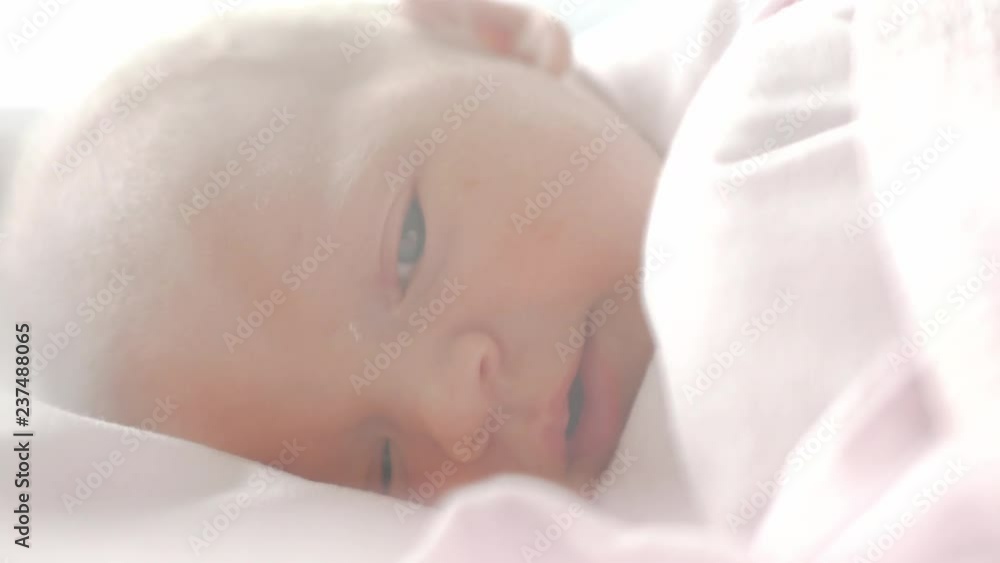 Close up shot of a newborn baby with blue eyes falling asleep while still in the hospital Close up shot of a newborn baby with blue eyes falling asleep while still in the hospital
