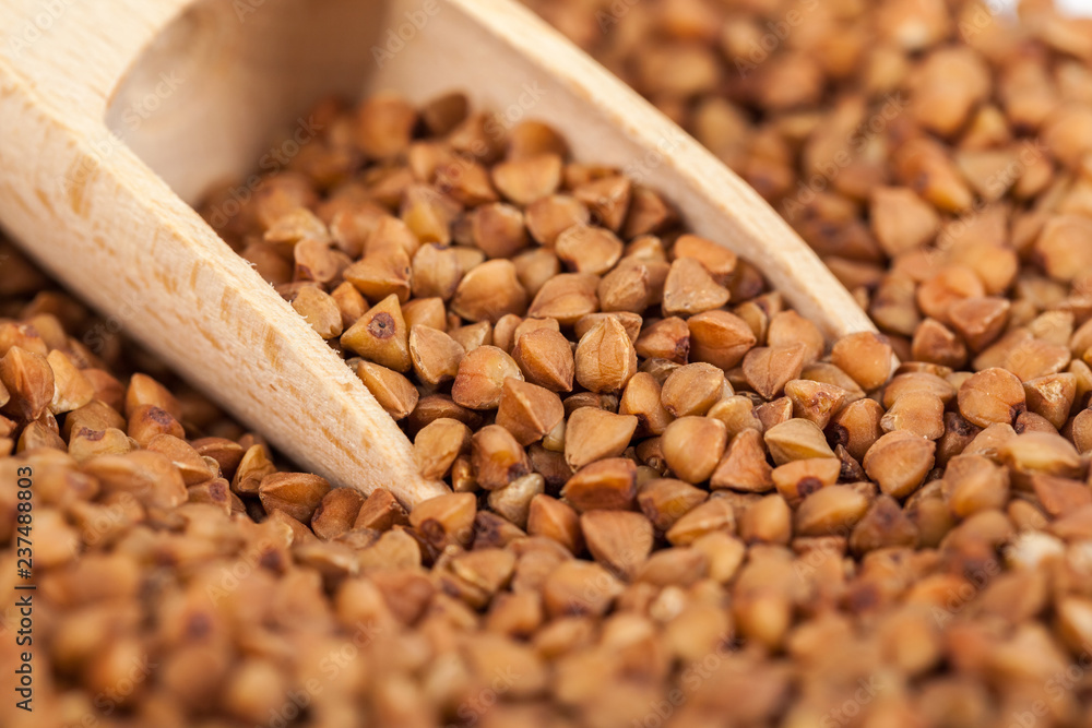 Group of buckwheat groats in a wooden spoon, healthy food Group of buckwheat groats in a wooden spoon, healthy food