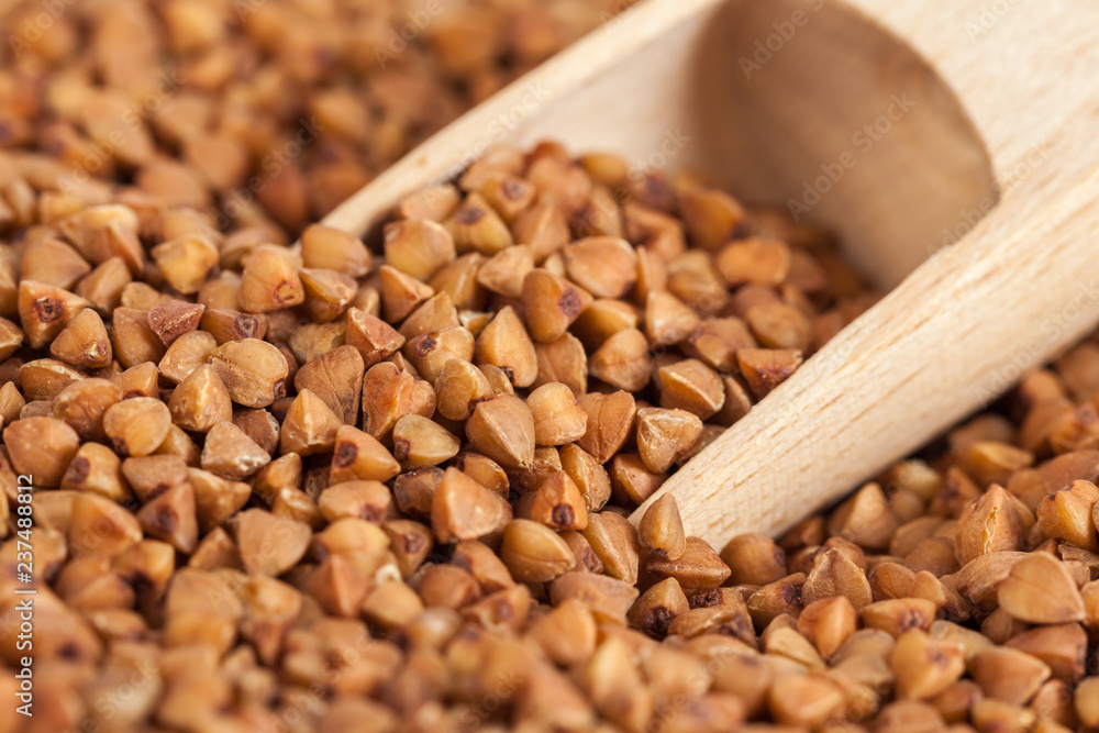 Group of buckwheat groats in a wooden spoon, healthy food Group of buckwheat groats in a wooden spoon, healthy food