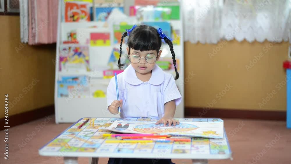 A cute little child Asian school girl doing homework and learn how to painting color. Kid enjoy learning with happiness at school. Clever,Education and smart learning concept A cute little child Asian school girl doing homework and learn how to painting color. Kid enjoy learning with happiness at school. Clever,Education and smart learning concept