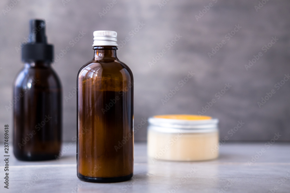 Spa cosmetics in bottles on gray concrete table. Copy space for text. Beauty blogging, salon therapy, branding mockup, minimalism concept Spa cosmetics in bottles on gray concrete table. Copy space for text. Beauty blogging, salon therapy, branding mockup, minimalism concept
