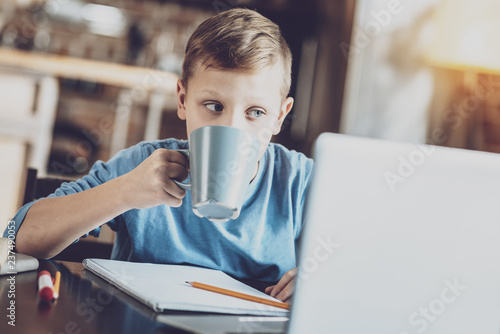 Concentrated kid drinking warm tea