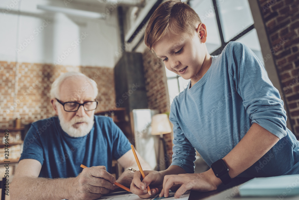 Fototapeta premium Concentrated gray-haired man drawing sketch