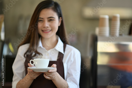 Barista in apron holding coffee in coffee shop