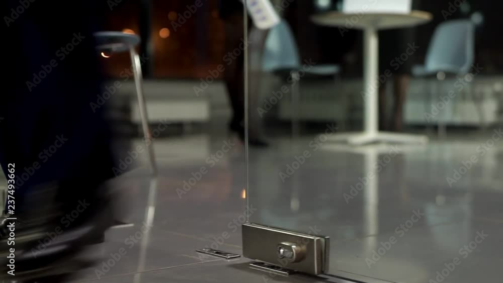 A glass door opens, men's black shoes come in from the office. A glass door opens, men's black shoes come in from the office.