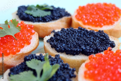 Red and black caviar of fish lies on wheat bread