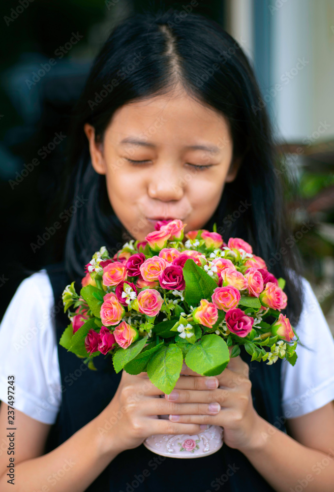 Blurred of Asian pre teen girl holding beautiful bouquet of pink and red roses. Smiling young pretty girl smelling big bunch of colorful flowers with soft focus. kid give flowers to someone. Blurred of Asian pre teen girl holding beautiful bouquet of pink and red roses. Smiling young pretty girl smelling big bunch of colorful flowers with soft focus. kid give flowers to someone.