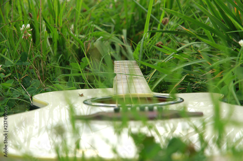 Acoustic wooden beige guitar closeup photography. Laying on the grass. blurred grass in front view. background image
