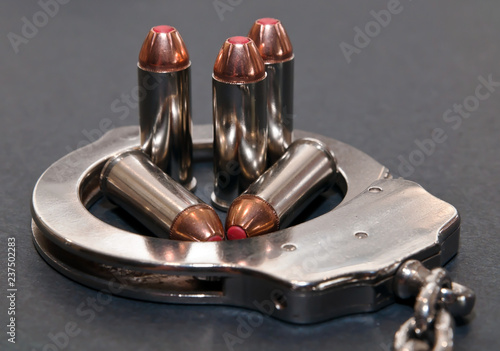 Five 44spl red tipped bullets inside of a metal handcuff on a gray background photo