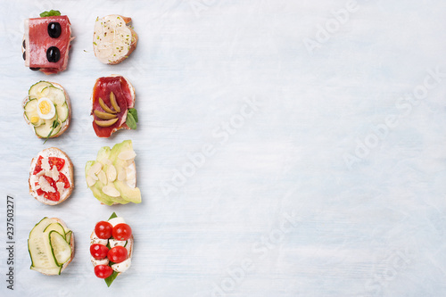 Various canapes on parchment paper on a wooden blue background.