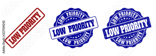 LOW PRIORITY grunge stamp seals in red and blue colors. Vector LOW PRIORITY marks with grunge effect. Graphic elements are rounded rectangles, rosettes, circles and text labels.