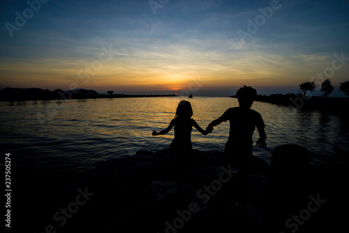 silhouette of Mom and daugther on the beach with sun set view.