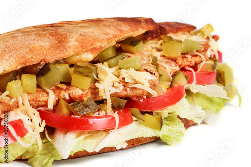 Sandwich from fresh pita bread with fillet grilled chicken, lettuce, slices of fresh tomatoes, pickles and cheese on white background