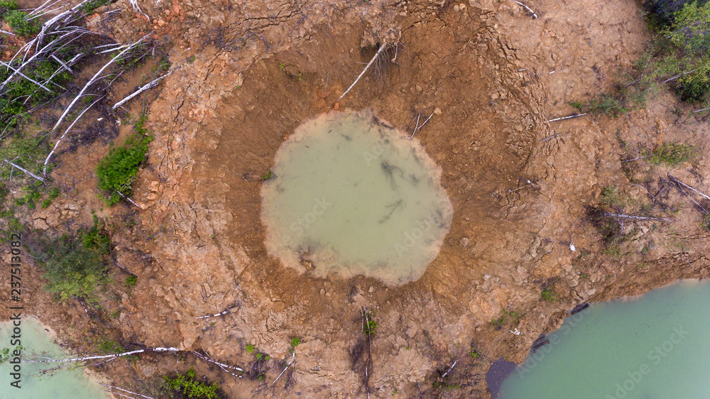Holes on ground from powerful explosions. Bomb craters in the forest. Disposal of explosives. Top view aerial photo from flying drone. - obrazy, fototapety, plakaty 