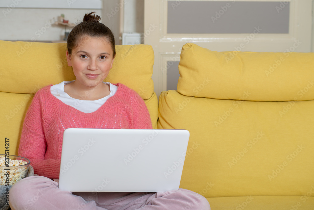 smiling teenage girl using laptop and eating popcorn smiling teenage girl using laptop and eating popcorn