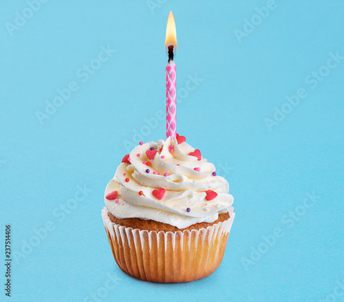 Cupcake with birthday candle on a blue background.
