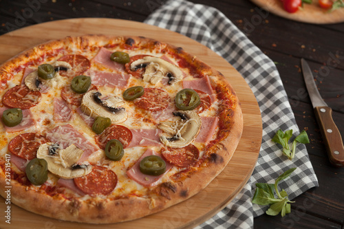 pizza, fresh pizza with mozzarella, tomatoes, pepporoni and cheese. Italian pizzeria. Fresh pizza on the kitchen table