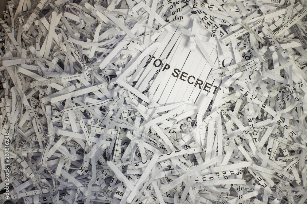 Cutted pieces of paper in a shredder basket. The cut lines of paper form the word Cutted pieces of paper in a shredder basket. The cut lines of paper form the word
