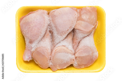 Frozen chicken legs in a yellow tray isolated on a white background. Raw chicken meat.