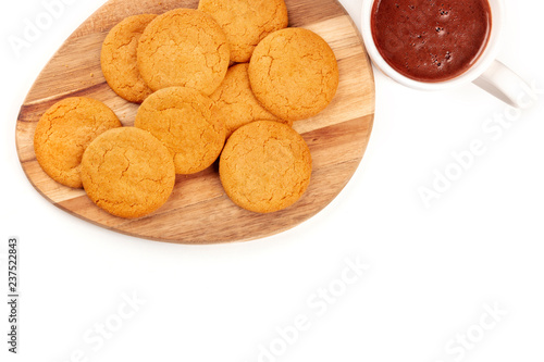 A closeup photo of gingersnaps with a mug of hot chocolate, shot from above on a white background with copy space