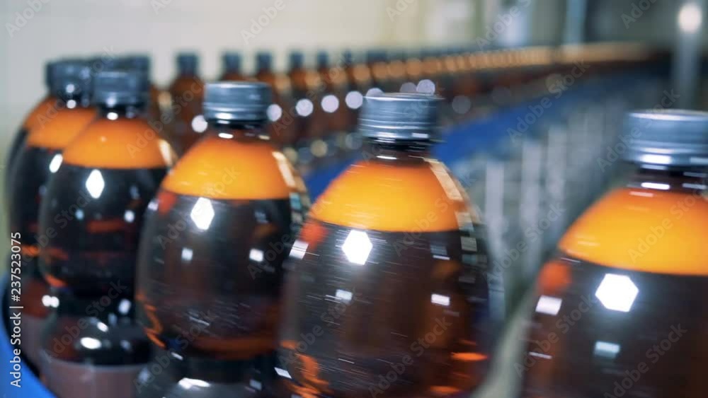 Lots of plastic bottles on a conveyor in a row, close up. Lots of plastic bottles on a conveyor in a row, close up.