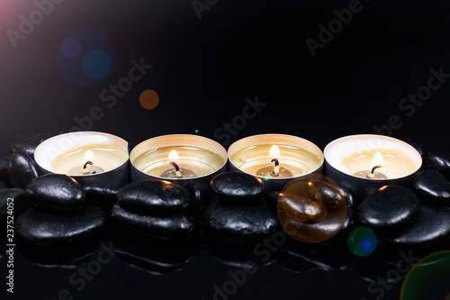 candles among black stones with reflection