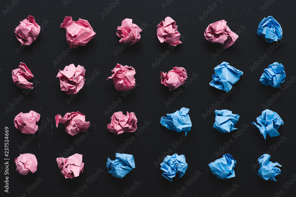 top view of arranged pink and blue crumpled paper balls on black background, think different concept top view of arranged pink and blue crumpled paper balls on black background, think different concept