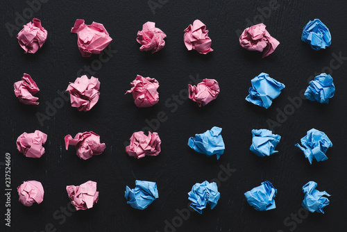 top view of arranged pink and blue crumpled paper balls on black background, think different concept