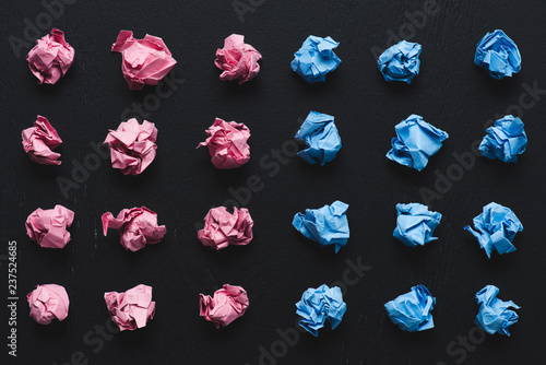 top view of arranged pink and blue crumpled paper balls on black background, think different concept