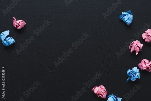 Fototapeta Naklejka Na Ścianę i Meble -  top view of scattered pink and blue crumpled paper balls on black background, think different concept