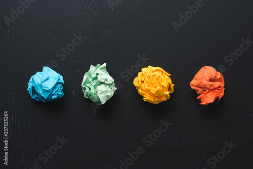 top view of arranged colorful crumpled paper balls on black background, think different concept