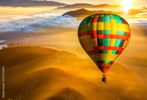 hot air balloon flying over misty mountains at sunrise - freedom and travel concept