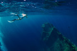Free diver man swimming in sea near shipwreck in Bali