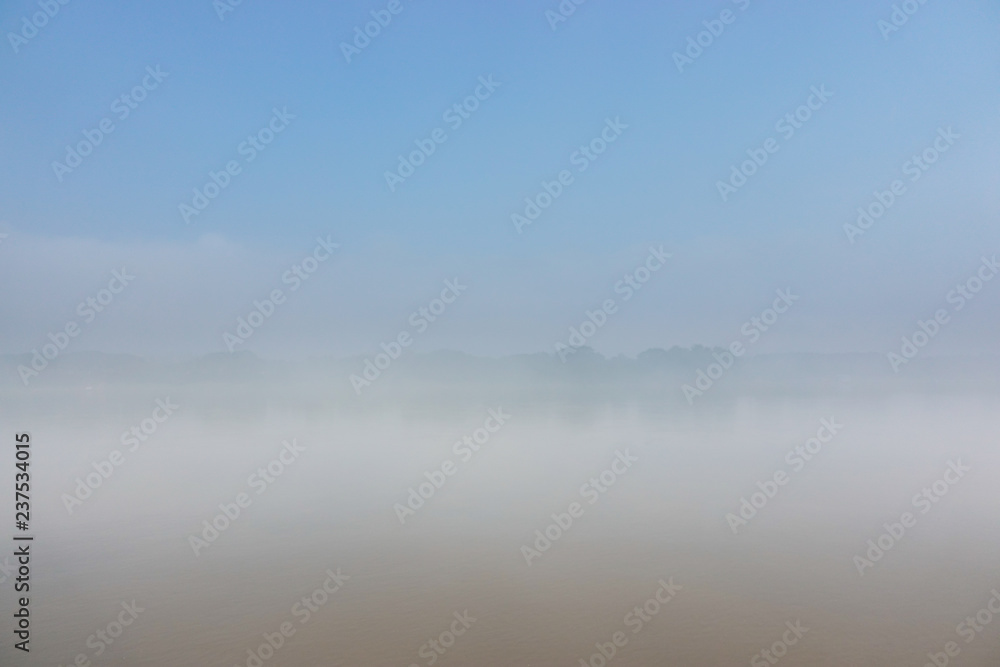 The dense morning mist covers the river and overlooks some of the opposite coasts