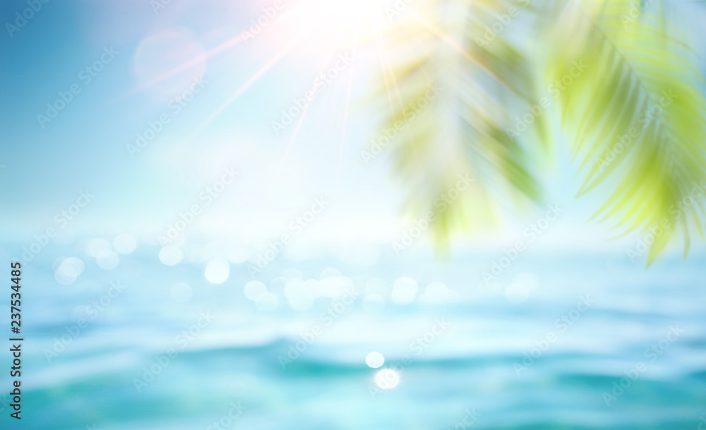 Abstract blur defocused background, toned gently blue, nature of tropical summer, rays of sun light. Beautiful sun glare on sea water and palm leaves against sky. Copy space, summer vacation concept.
