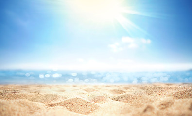 Abstract blur defocused background, nature of tropical summer beach with rays of sun light. Golden sand beach, sea water against blue sky with white clouds. Copy space, summer vacation concept.