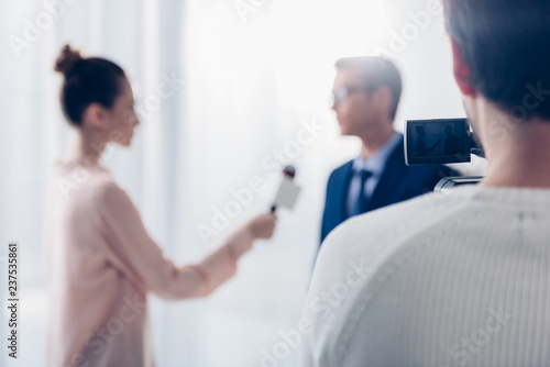 selective focus of businessman in glasses giving video interview to journalist in office