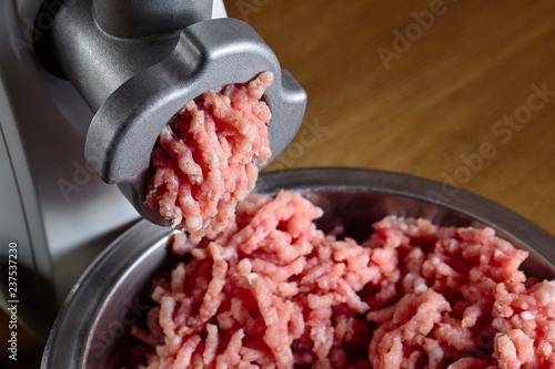 Minced meat coming out from modern electric grinder on oak table as background. Healthy fresh homemade minced meat. Place for copyspace