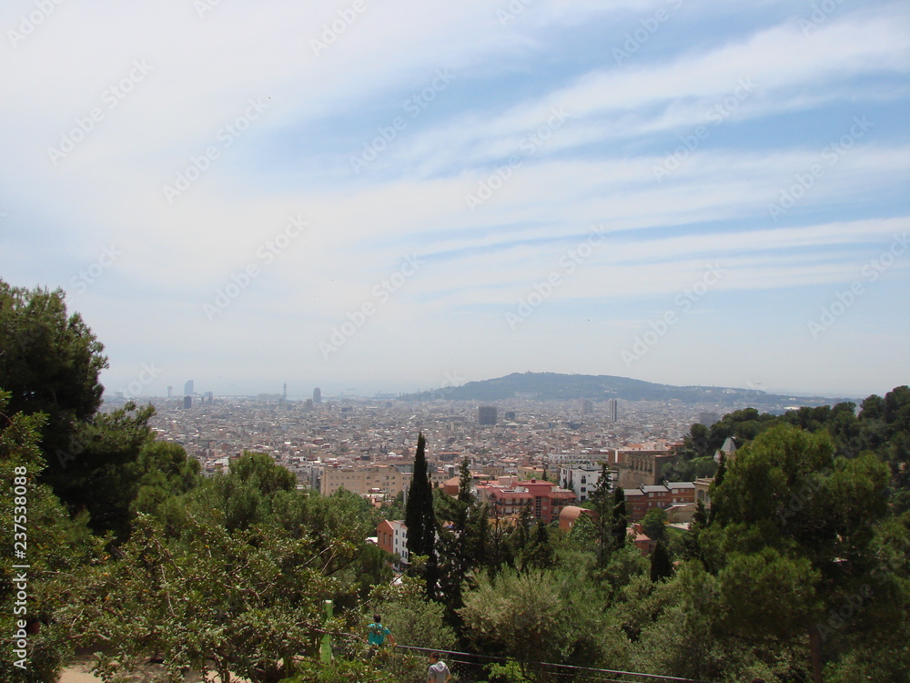 Panorama of cloudy blue sky over the streets and parks of the city against the backdrop of a mountain range on the horizon.