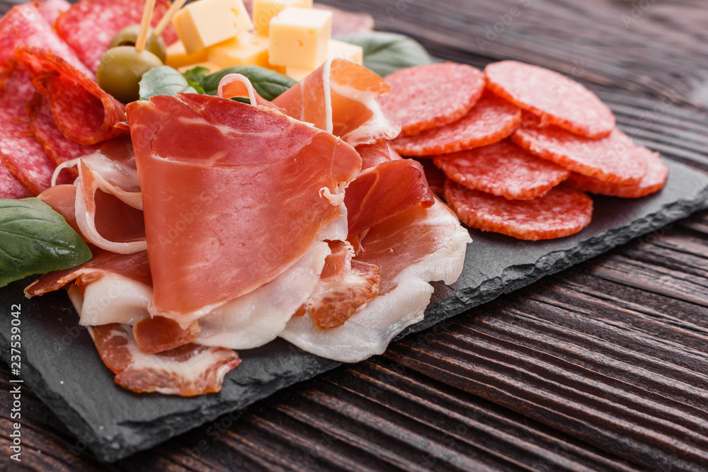 Cold smoked meat plate on a rustic wooden background Cold smoked meat plate on a rustic wooden background