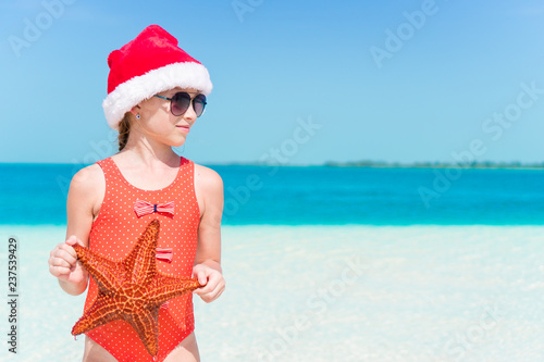 Adorable little girl in Santa hat during Christmas beach vacation