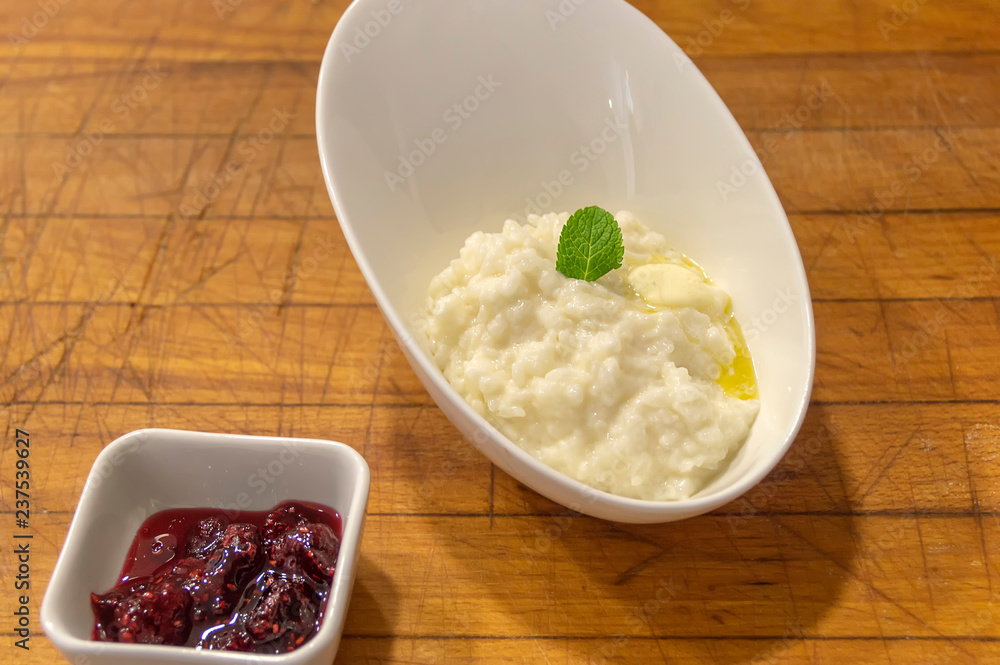 rice porridge with butter in a plate, decorated with a mint leaf, next to a dish filled with strawberry jam rice porridge with butter in a plate, decorated with a mint leaf, next to a dish filled with strawberry jam