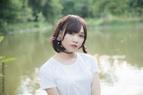 Fototapeta Naklejka Na Ścianę i Meble -  portrait of asian girl with white shirt and skirt looking in outdoor nature vintage film style