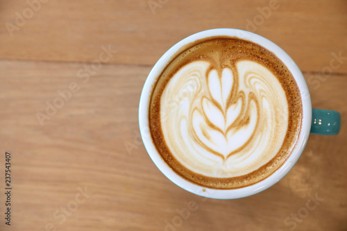 Hot cappuccino coffee in coffee shop on wooden table