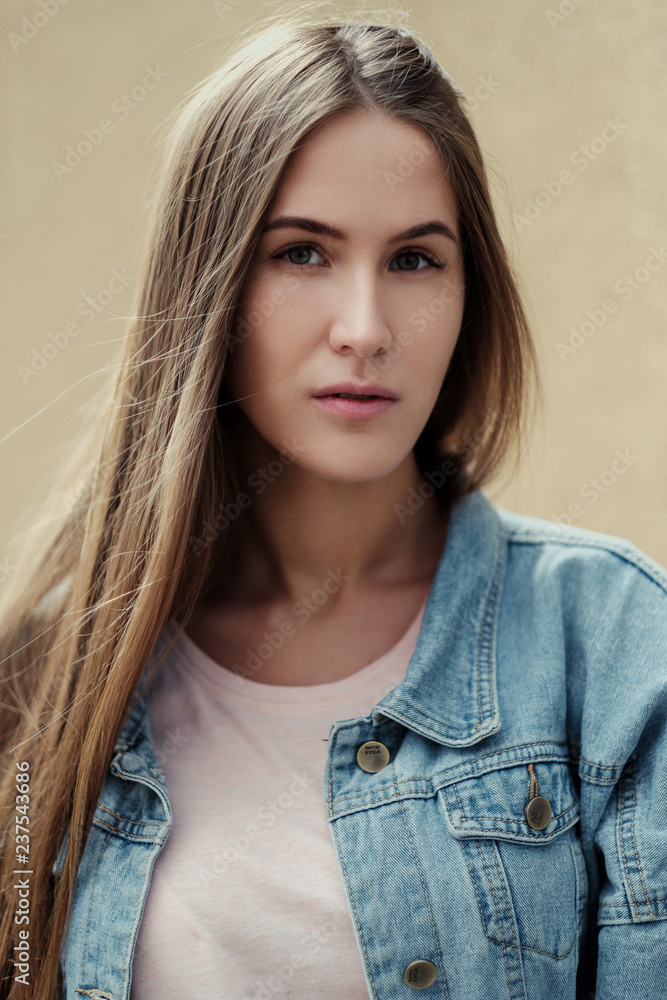 Young beautiful girl with long hair in a T-shirt and denim jacket on the background of vintage concrete wall. Young beautiful girl with long hair in a T-shirt and denim jacket on the background of vintage concrete wall.