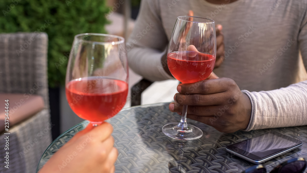 Black couple holding wine glasses, celebrating anniversary with girlfriend