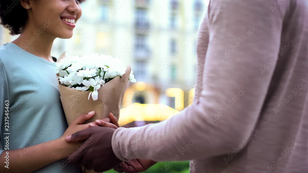 Male presenting flowers to pretty girlfriend, hugging on summer date, surprise Male presenting flowers to pretty girlfriend, hugging on summer date, surprise